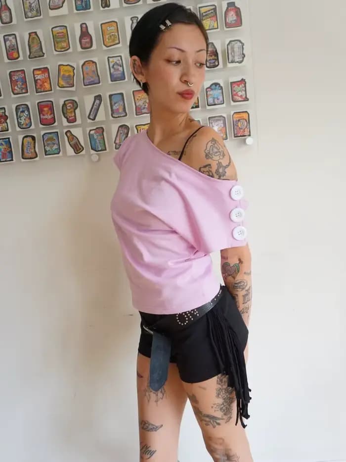 T-shirt rose à épaules dénudées pour femme avec encolure asymétrique et détail boutonné sur la manch